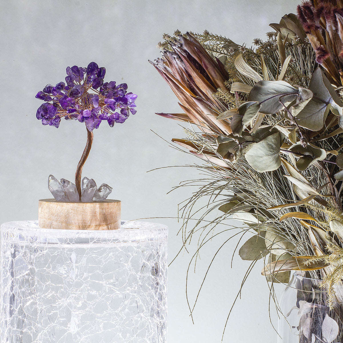 Indulge in a peaceful night&#39;s sleep next to a stunning crystal tree of life, carefully crafted to promote energetic healing and a serene ambiance. Immerse yourself in the gentle, calming glow emanating from the precisely cut clear quartz points, arranged meticulously on a natural, visually appealing wooden base. Accentuating the entire structure is a delicate copper wire stem, elegantly adorned with your choice of crystal chip leaf topping.