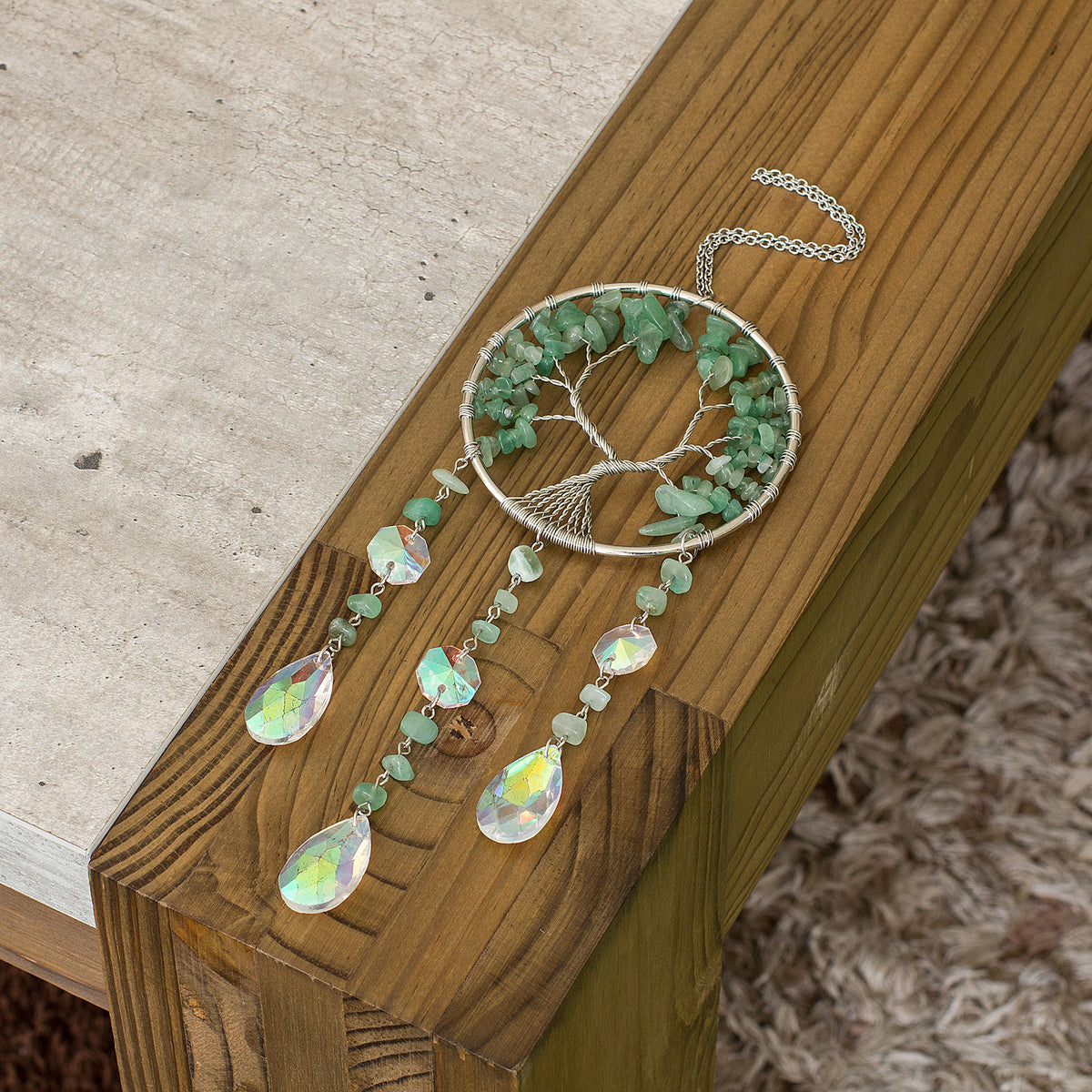 Enhance the ambiance of your living space with the enchanting allure of this stunning crystal chip suncatcher. Experience the mesmerizing spectacle as the glass teardrop scatters a breathtaking spectrum of rainbow hues, casting a spellbinding and vibrant radiance throughout your home. Adorned with a crystal chip tree of life, this suncatcher exudes a sense of warmth and tranquility, adding a touch of elegance to your home decor. Elevate the atmosphere of your living space with this captivating and spellbind
