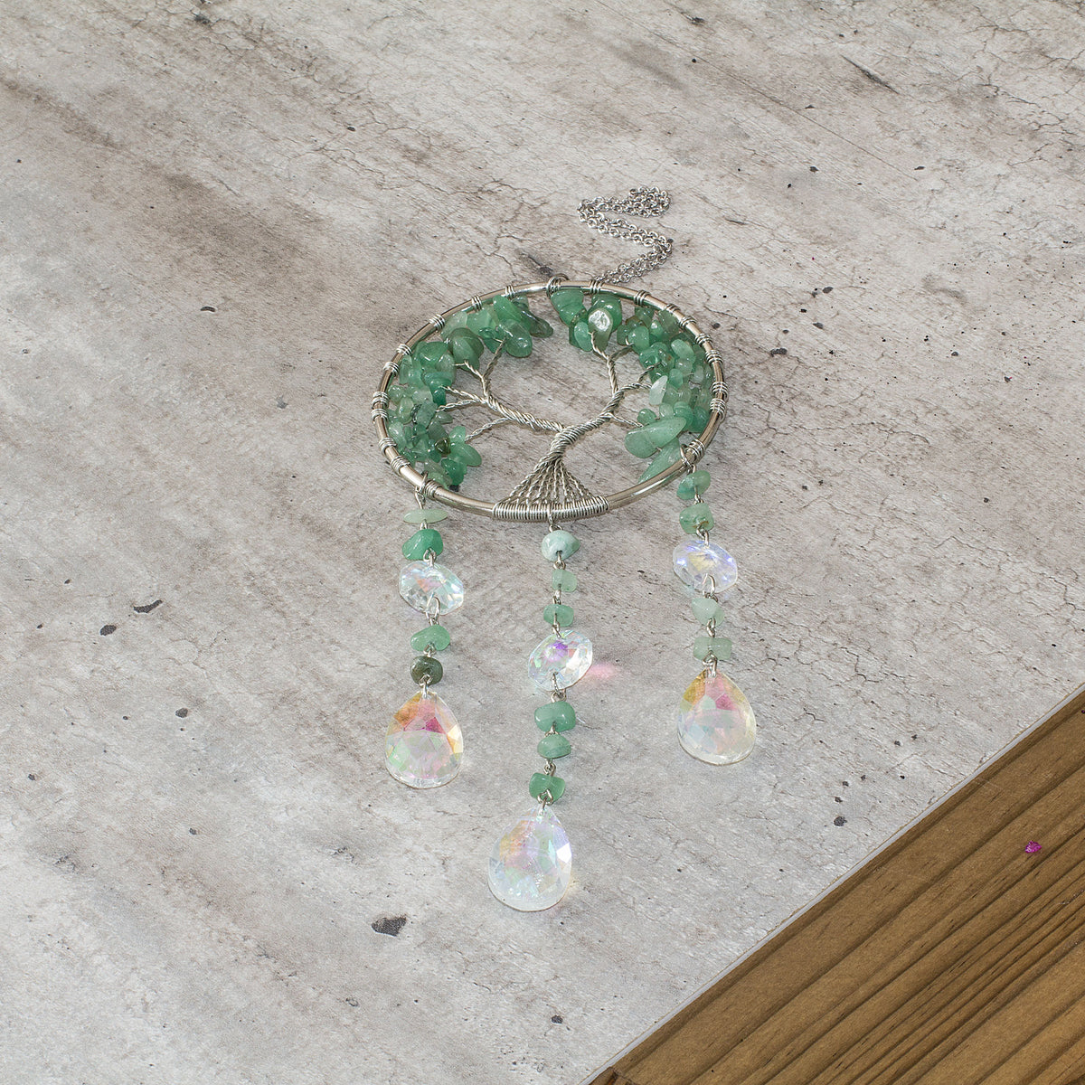 Enhance the ambiance of your living space with the enchanting allure of this stunning crystal chip suncatcher. Experience the mesmerizing spectacle as the glass teardrop scatters a breathtaking spectrum of rainbow hues, casting a spellbinding and vibrant radiance throughout your home. Adorned with a crystal chip tree of life, this suncatcher exudes a sense of warmth and tranquility, adding a touch of elegance to your home decor. Elevate the atmosphere of your living space with this captivating and spellbind