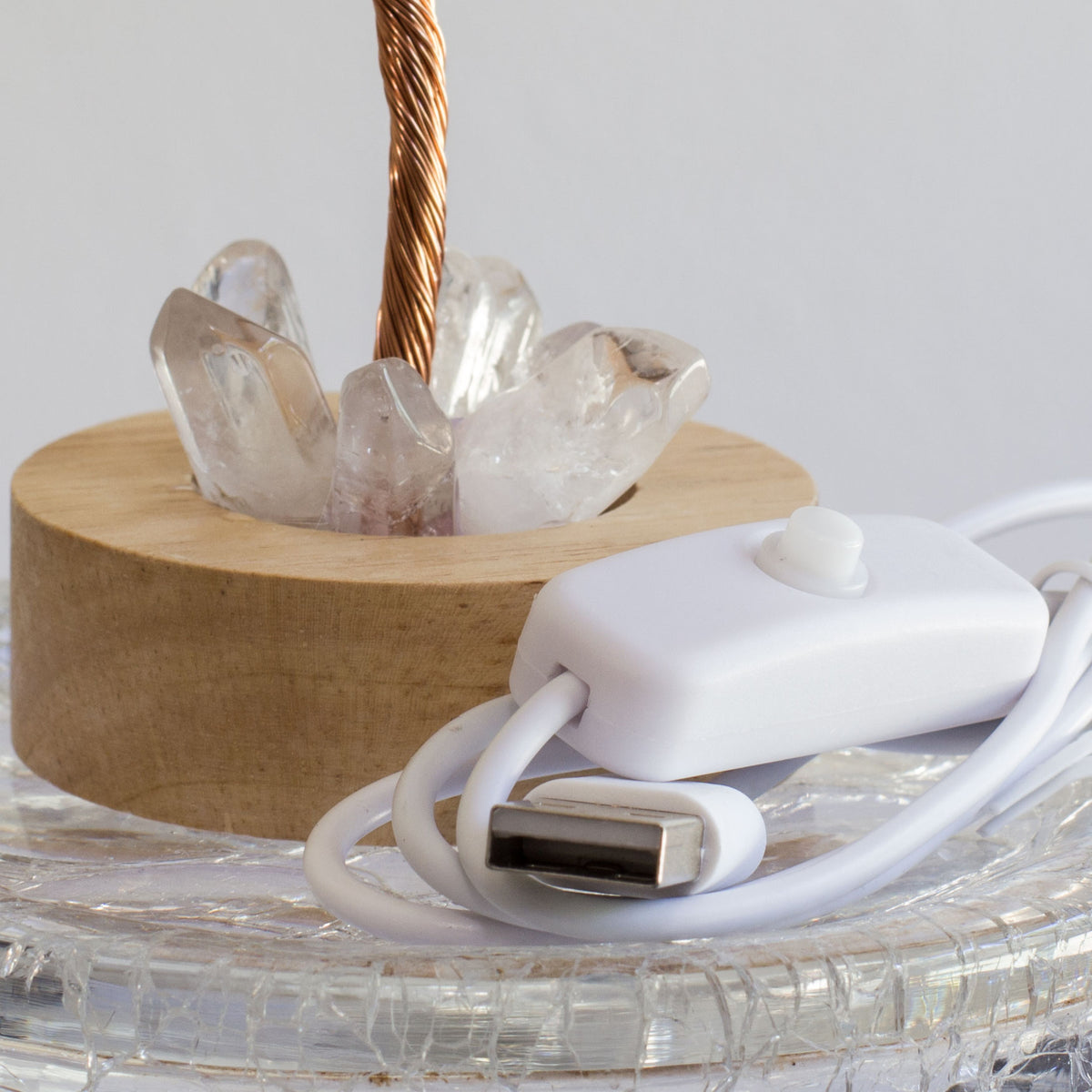Indulge in a peaceful night&#39;s sleep next to a stunning crystal tree of life, carefully crafted to promote energetic healing and a serene ambiance. Immerse yourself in the gentle, calming glow emanating from the precisely cut clear quartz points, arranged meticulously on a natural, visually appealing wooden base. Accentuating the entire structure is a delicate copper wire stem, elegantly adorned with your choice of crystal chip leaf topping.