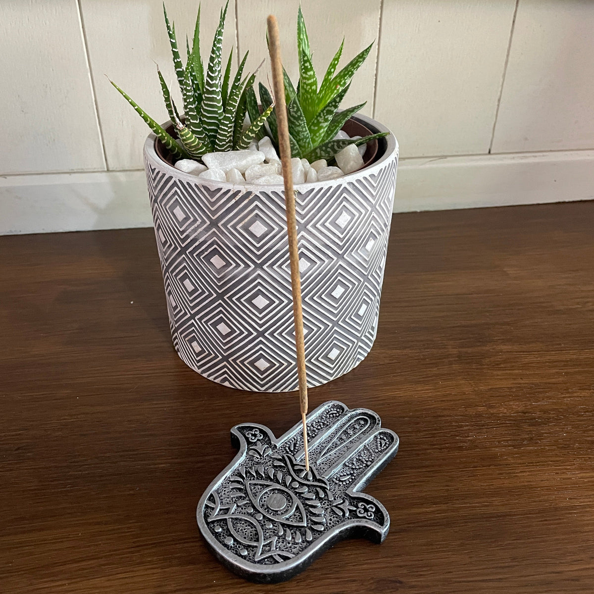 Hamsa Hand Metal Incense holder (Silver) Mi Chakra - Introducing a stylish metal Hamsa Hand incense holder, a beautifully crafted piece that seamlessly blends elegance with functionality. This unique design not only enhances the aesthetic of your space but also serves as a perfect resting place for your favorite incense sticks. The intricate detailing of the Hamsa hand symbolizes protection and good fortune, making it a meaningful addition to your home decor. Whether you&#39;re looking to create a serene atmosp