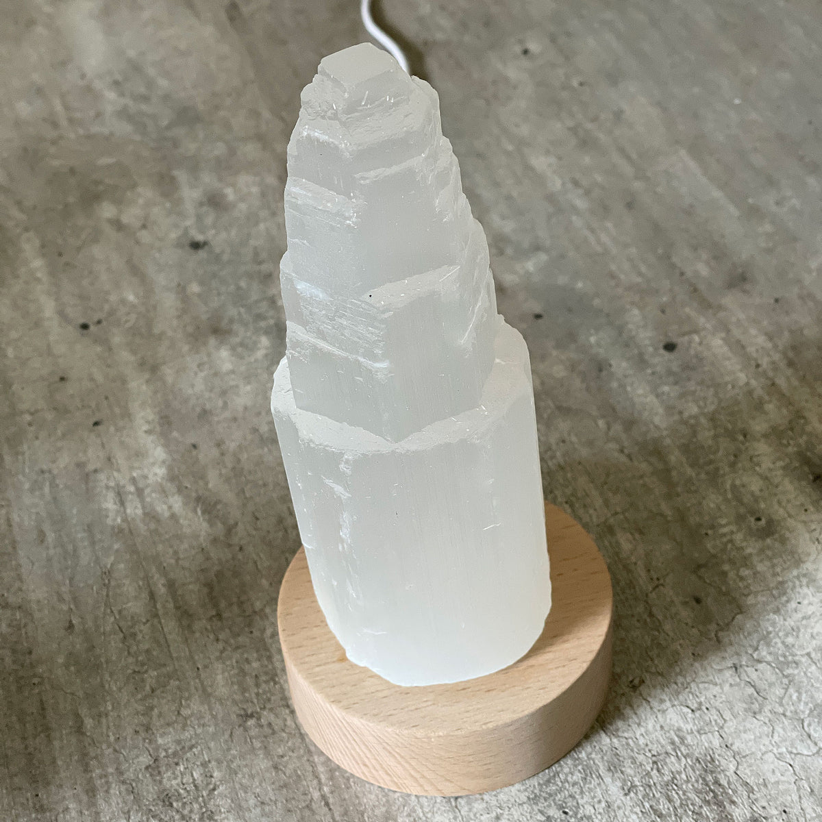 Selenite Lamp - Tower Small - Selenite is a beautiful and versatile crystal that offers numerous benefits, making it a popular choice for both decor and holistic purposes. Its natural beauty and unique translucent appearance make it an eye-catching addition to any home. Selenite emits a soft and warm glow, which makes it an excellent choice for a night light.