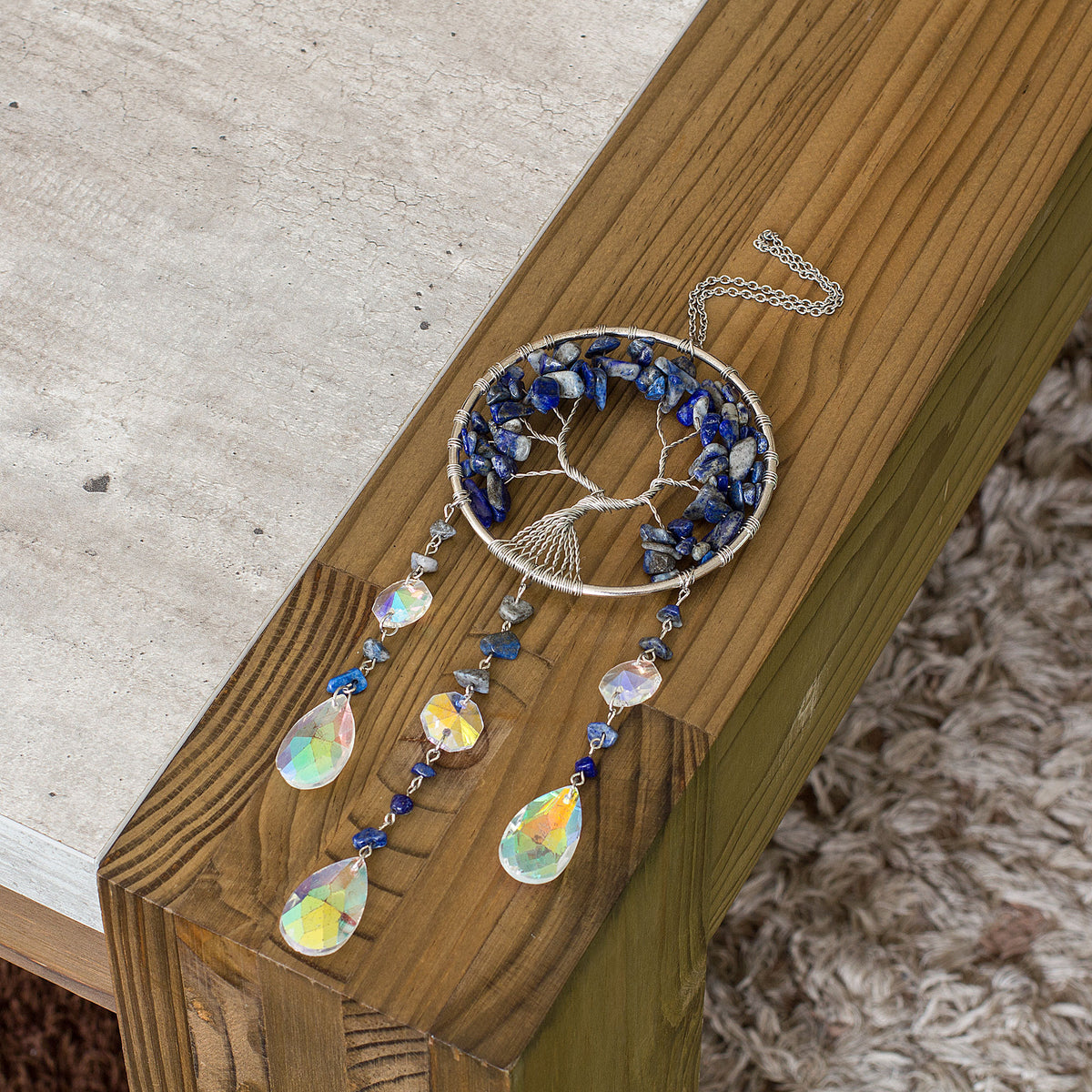 Enhance the ambiance of your living space with the enchanting allure of this stunning crystal chip suncatcher. Experience the mesmerizing spectacle as the glass teardrop scatters a breathtaking spectrum of rainbow hues, casting a spellbinding and vibrant radiance throughout your home. Adorned with a crystal chip tree of life, this suncatcher exudes a sense of warmth and tranquility, adding a touch of elegance to your home decor. Elevate the atmosphere of your living space with this captivating and spellbind