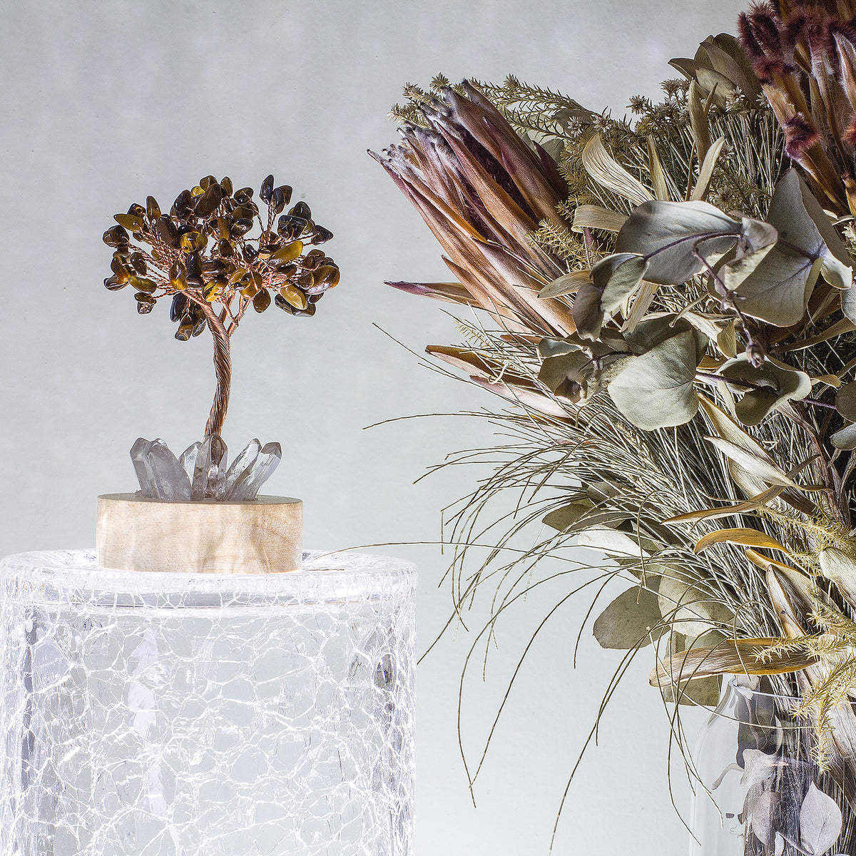 Indulge in a peaceful night&#39;s sleep next to a stunning crystal tree of life, carefully crafted to promote energetic healing and a serene ambiance. Immerse yourself in the gentle, calming glow emanating from the precisely cut clear quartz points, arranged meticulously on a natural, visually appealing wooden base. Accentuating the entire structure is a delicate copper wire stem, elegantly adorned with your choice of crystal chip leaf topping.