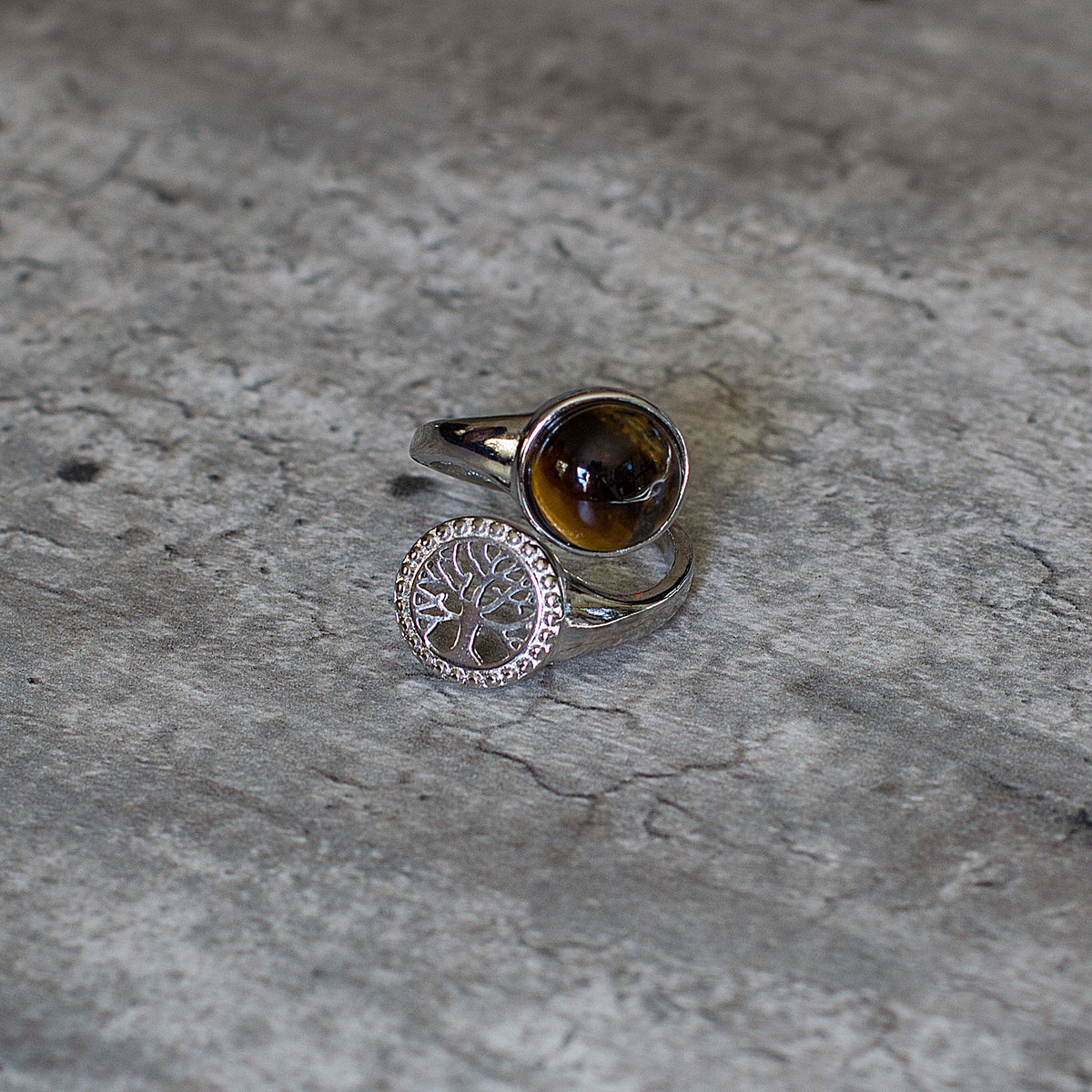 Are you drawn to the calming and grounding influence of crystals, and the liberating lifestyle they symbolize? If so, immerse yourself in the sheer beauty of our exclusive assortment of crystal rings. These exquisite wrap-around adjustable rings are a sight to behold, featuring a dazzling tree of life intricately set in a mesmerizing circular pattern, accentuated by a captivating and flawlessly cut round cabochon crystal at its center.