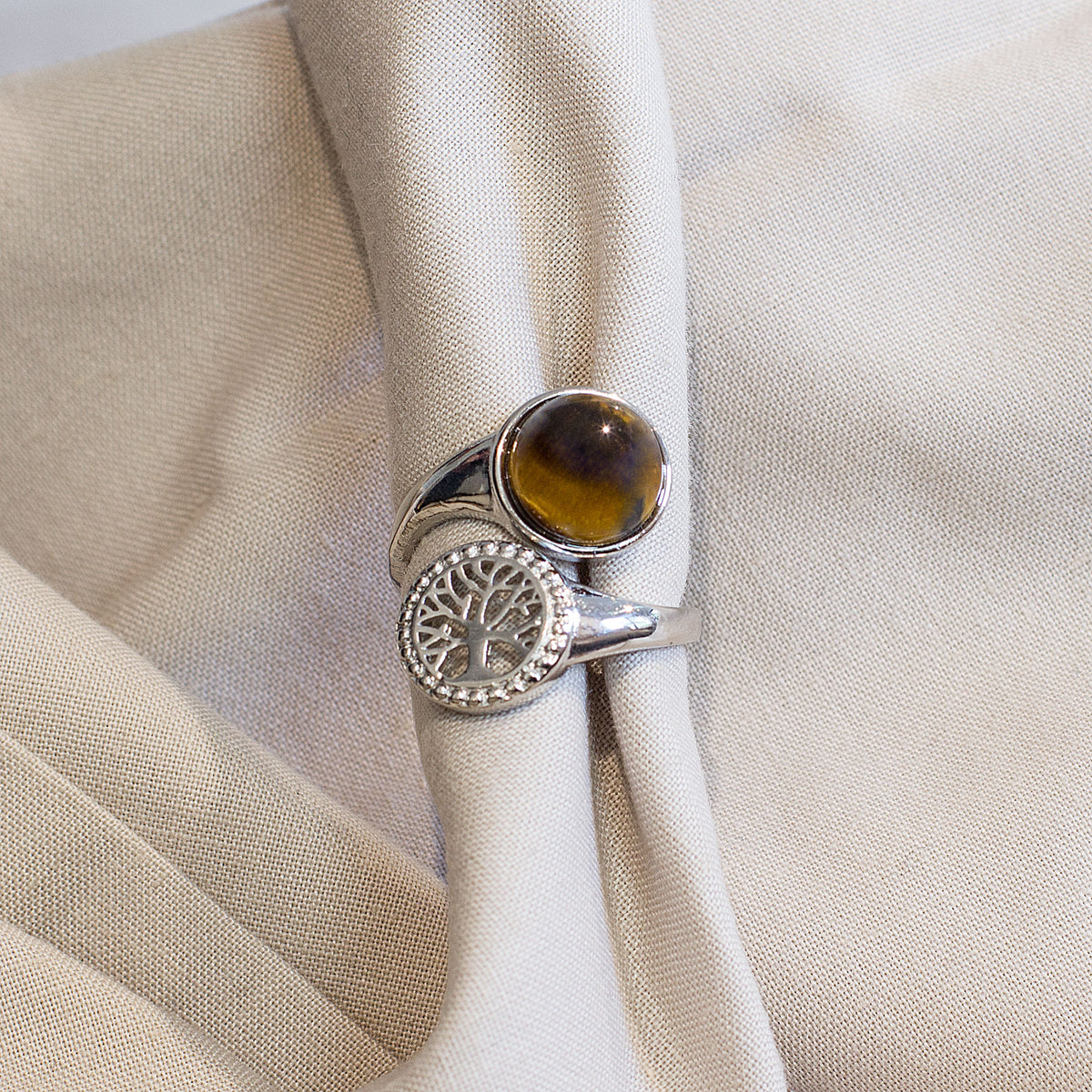Are you drawn to the calming and grounding influence of crystals, and the liberating lifestyle they symbolize? If so, immerse yourself in the sheer beauty of our exclusive assortment of crystal rings. These exquisite wrap-around adjustable rings are a sight to behold, featuring a dazzling tree of life intricately set in a mesmerizing circular pattern, accentuated by a captivating and flawlessly cut round cabochon crystal at its center.